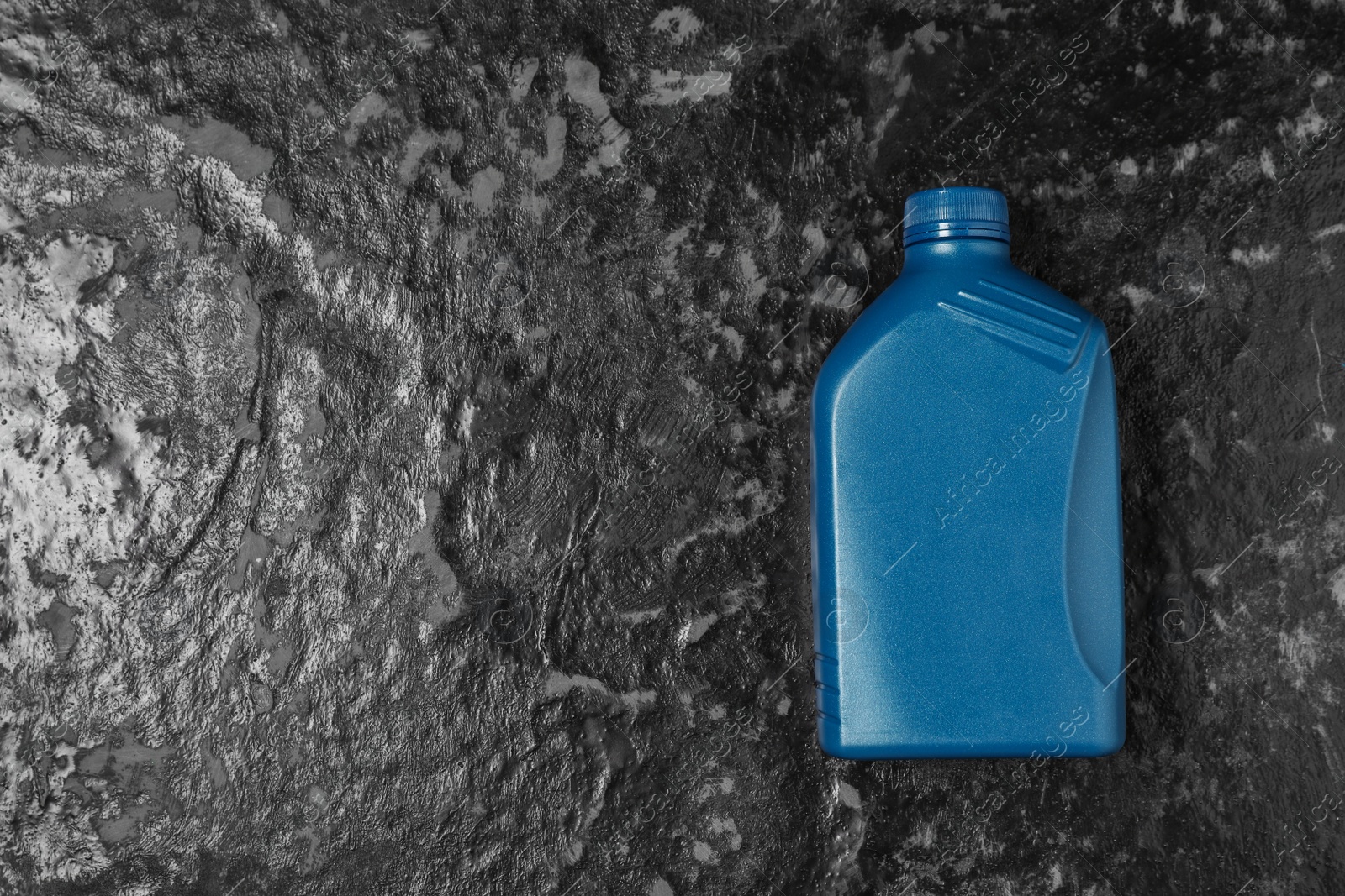 Photo of Motor oil in blue canister on black table, top view. Space for text