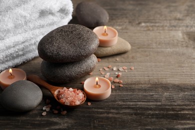 Photo of Beautiful composition with spa stones and burning candles on wooden table. Space for text