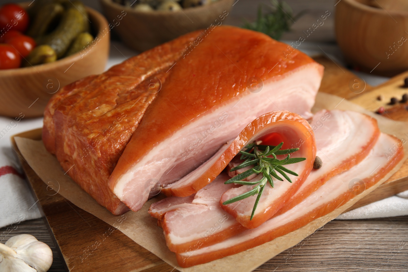 Photo of Delicious smoked bacon with rosemary on wooden table, closeup