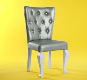 Stylish silver chair on yellow background, space for text. Element of interior design