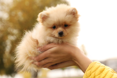 Woman with small fluffy dog outdoors on autumn day, closeup