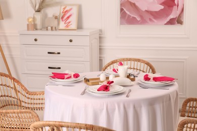 Photo of Color accent table setting. Plates, cutlery and pink napkins in dining room