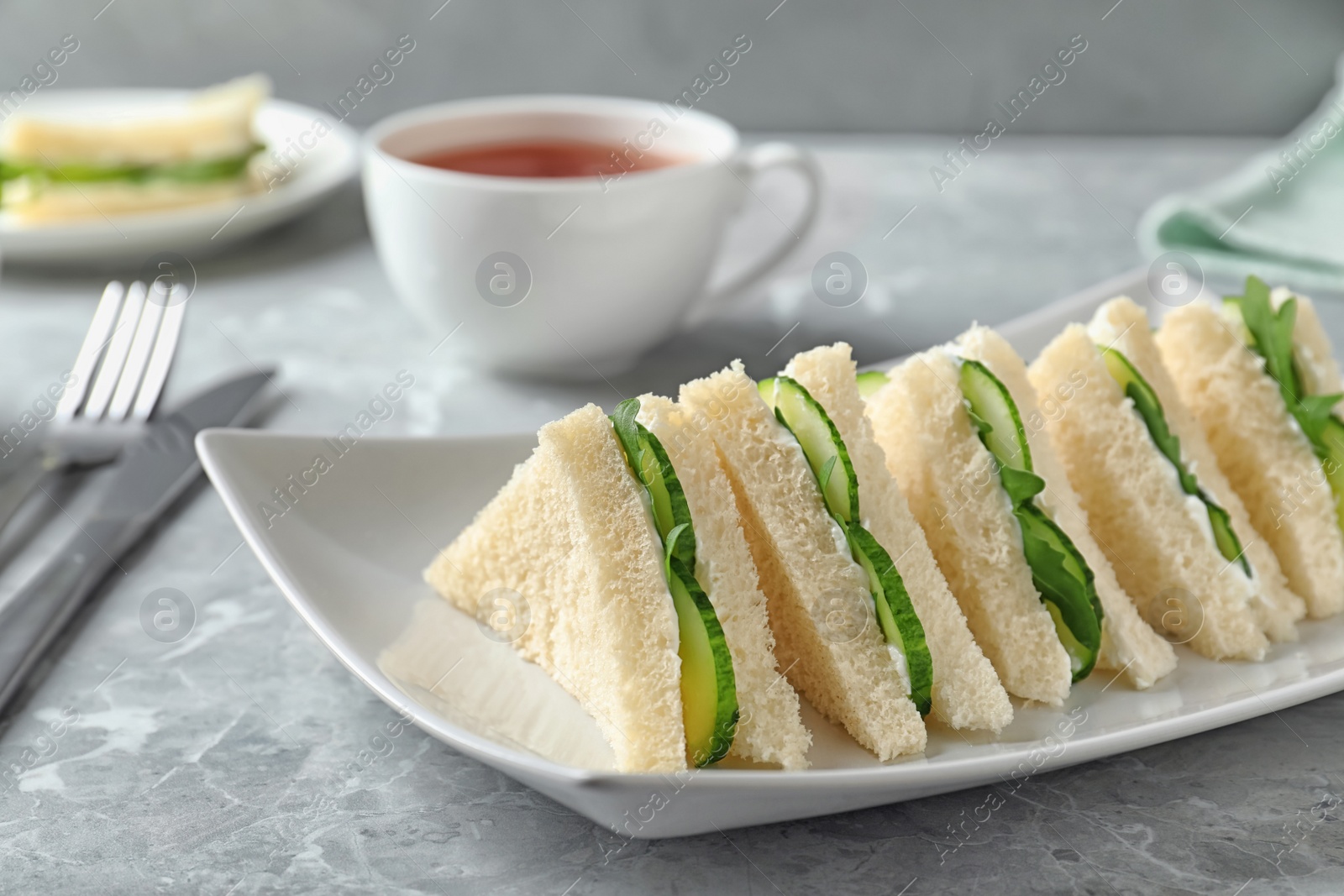 Photo of Plate with traditional English cucumber sandwiches on table