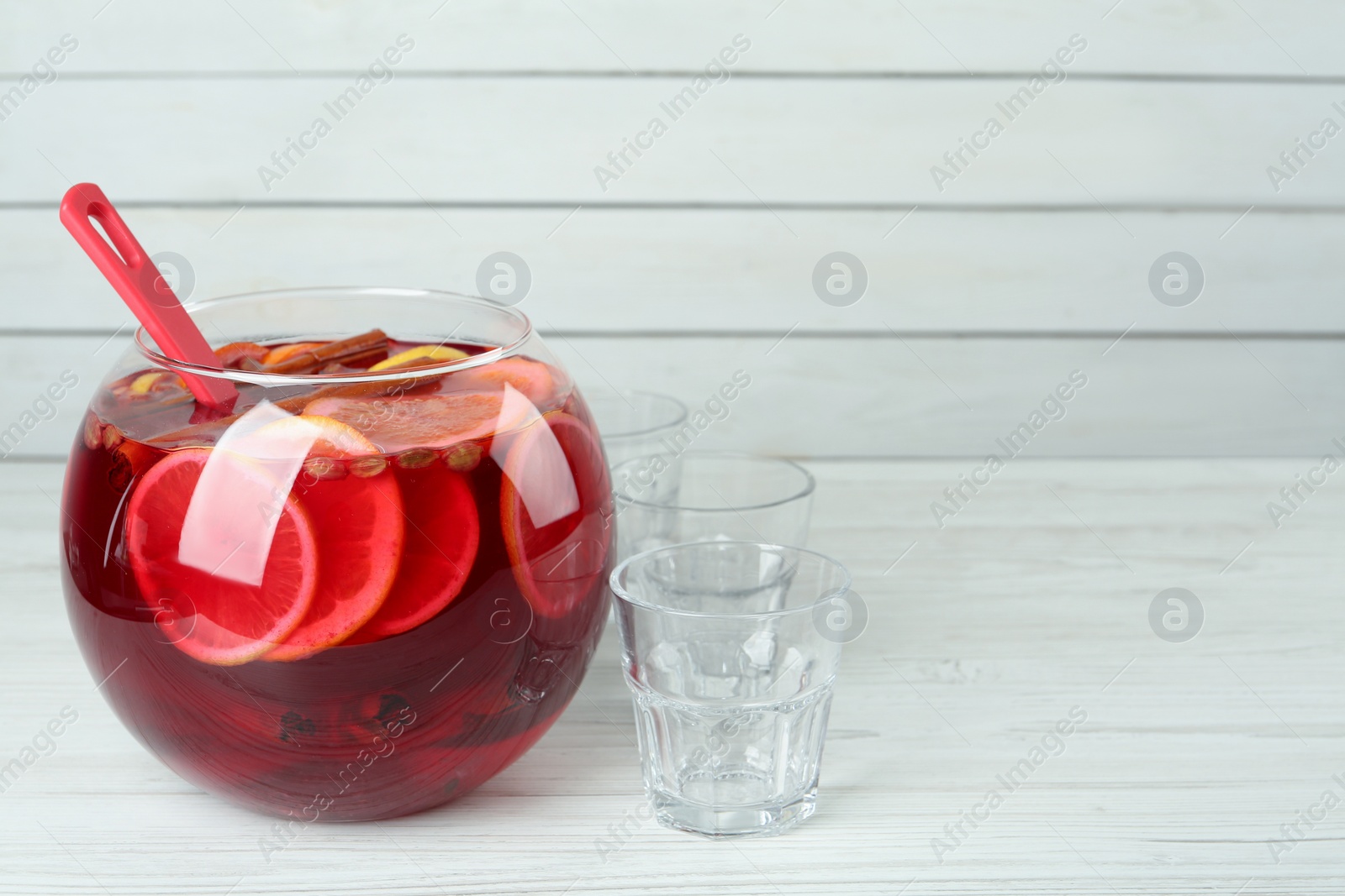 Photo of Empty glasses and ladle near bowl of aromatic punch drink on white wooden table, space for text