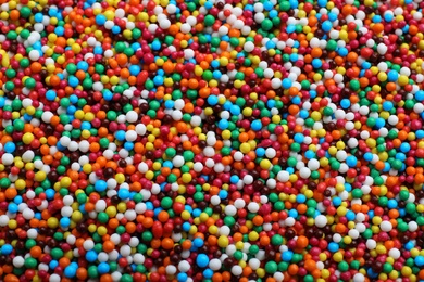 Bright colorful sprinkles as background, top view. Confectionery decor