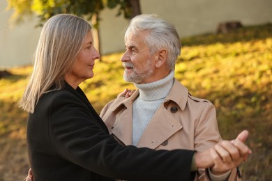 Photo of Affectionate senior couple dancing together outdoors. Romantic date