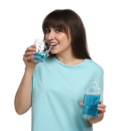 Young woman using mouthwash on white background