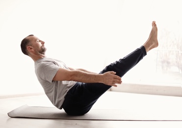 Sporty man practicing yoga indoors