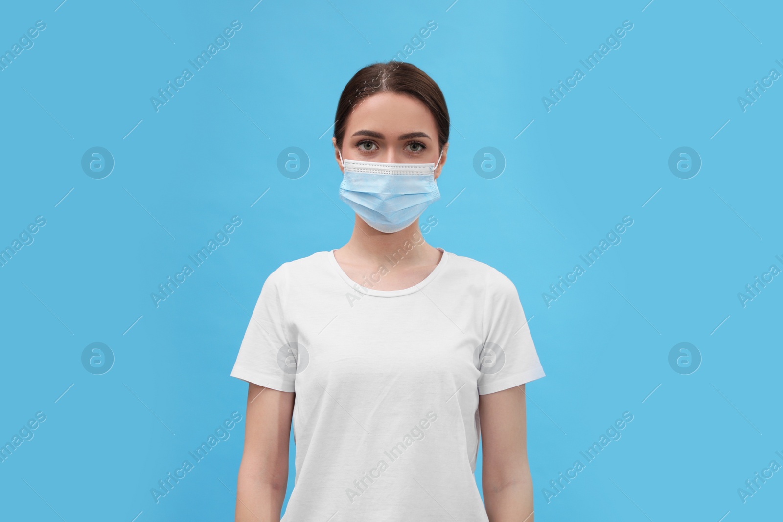 Photo of Portrait of woman in medical mask on light blue background