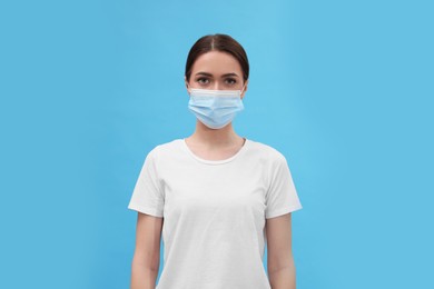 Portrait of woman in medical mask on light blue background