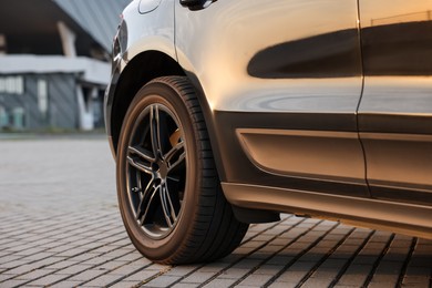 Photo of Modern car with big wheel parked on stone pavement outdoors, closeup