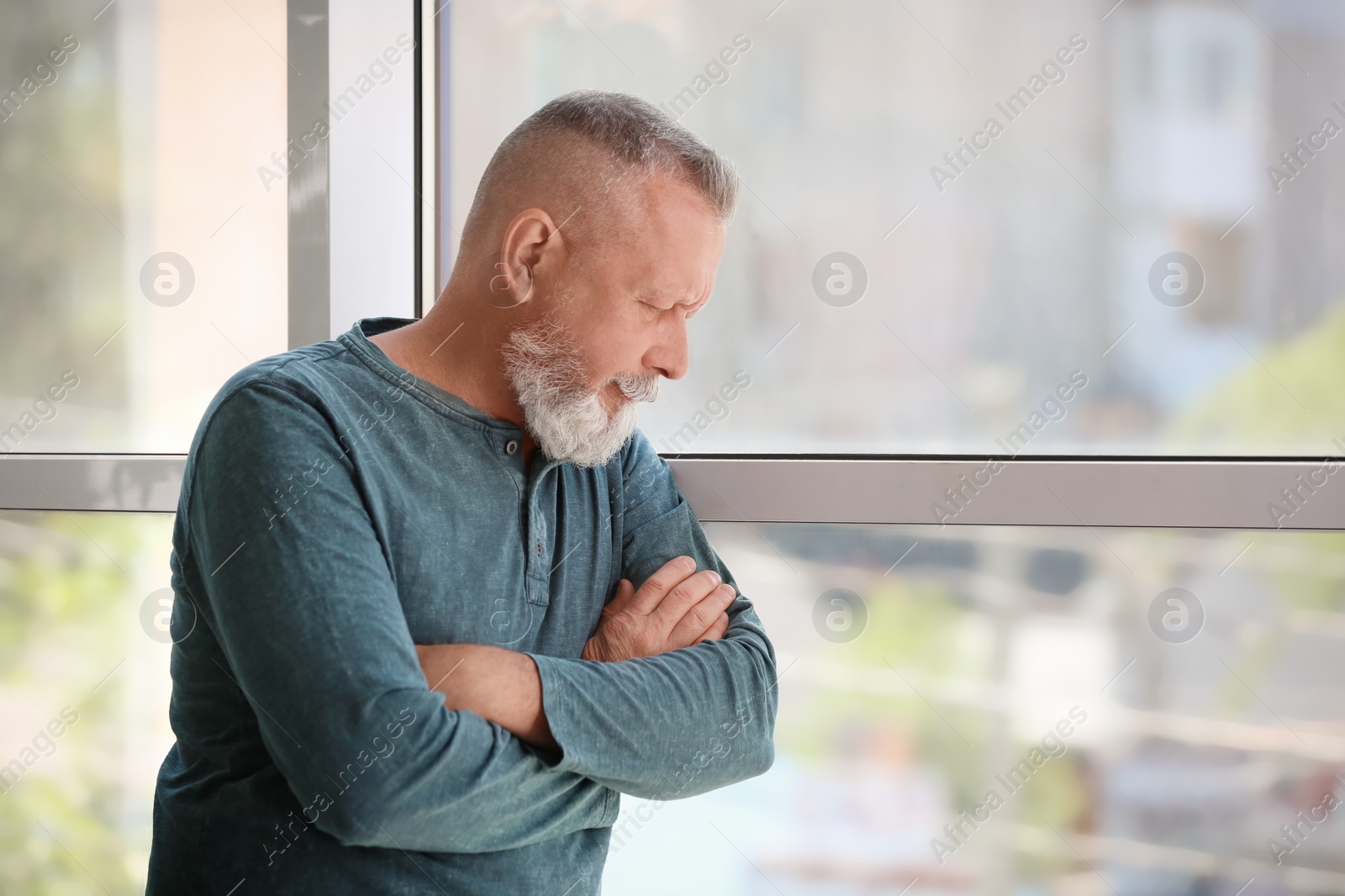 Photo of Depressed senior man near window indoors