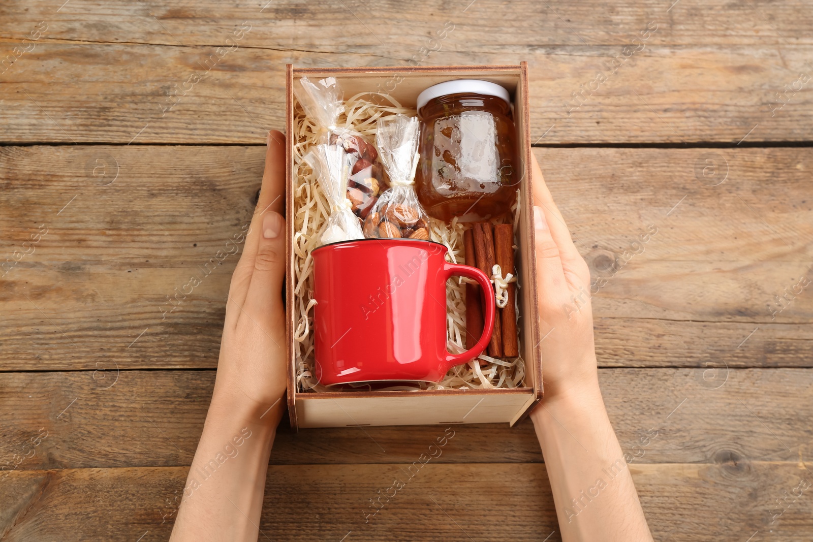 Photo of Woman holding box with stylish craft gift set at wooden table, above view