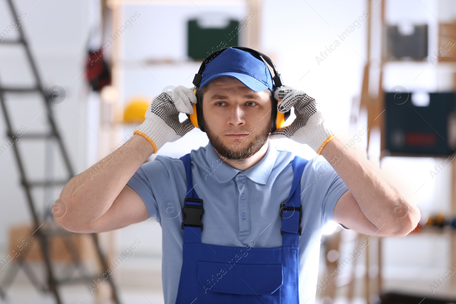 Photo of Worker wearing safety headphones indoors. Hearing protection device