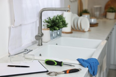 Photo of Plumbing tools and clipboard on countertop near sink in kitchen
