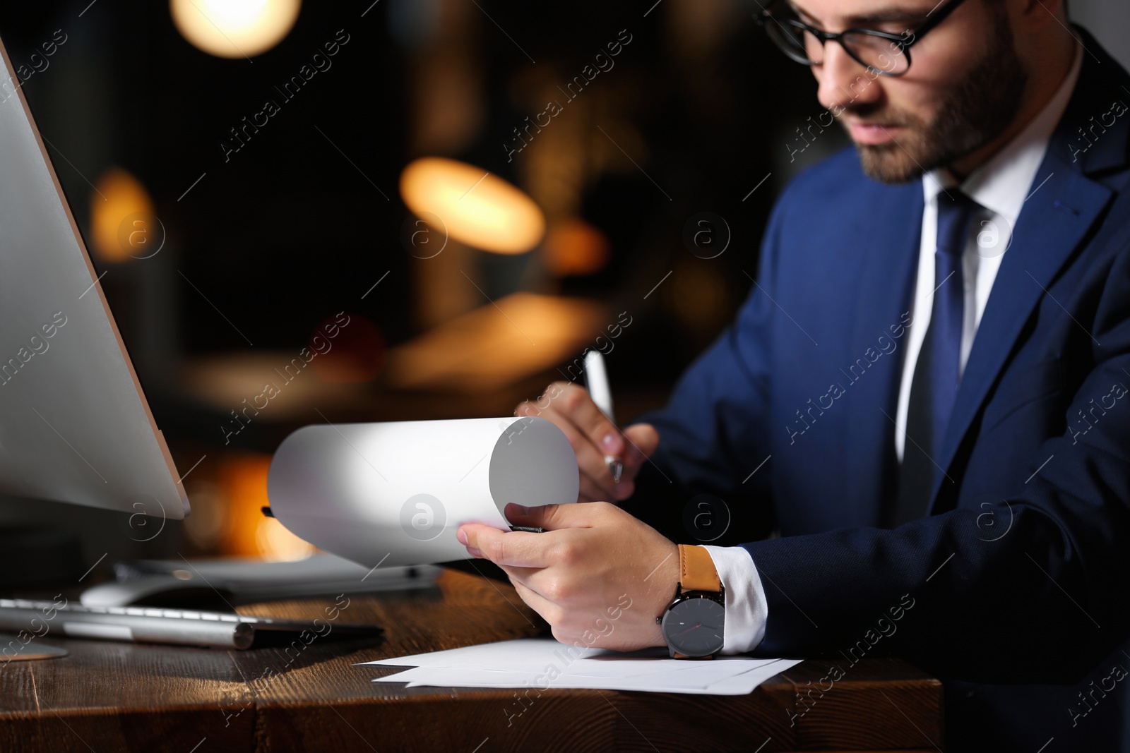 Photo of Young businessman working in office alone at night, closeup