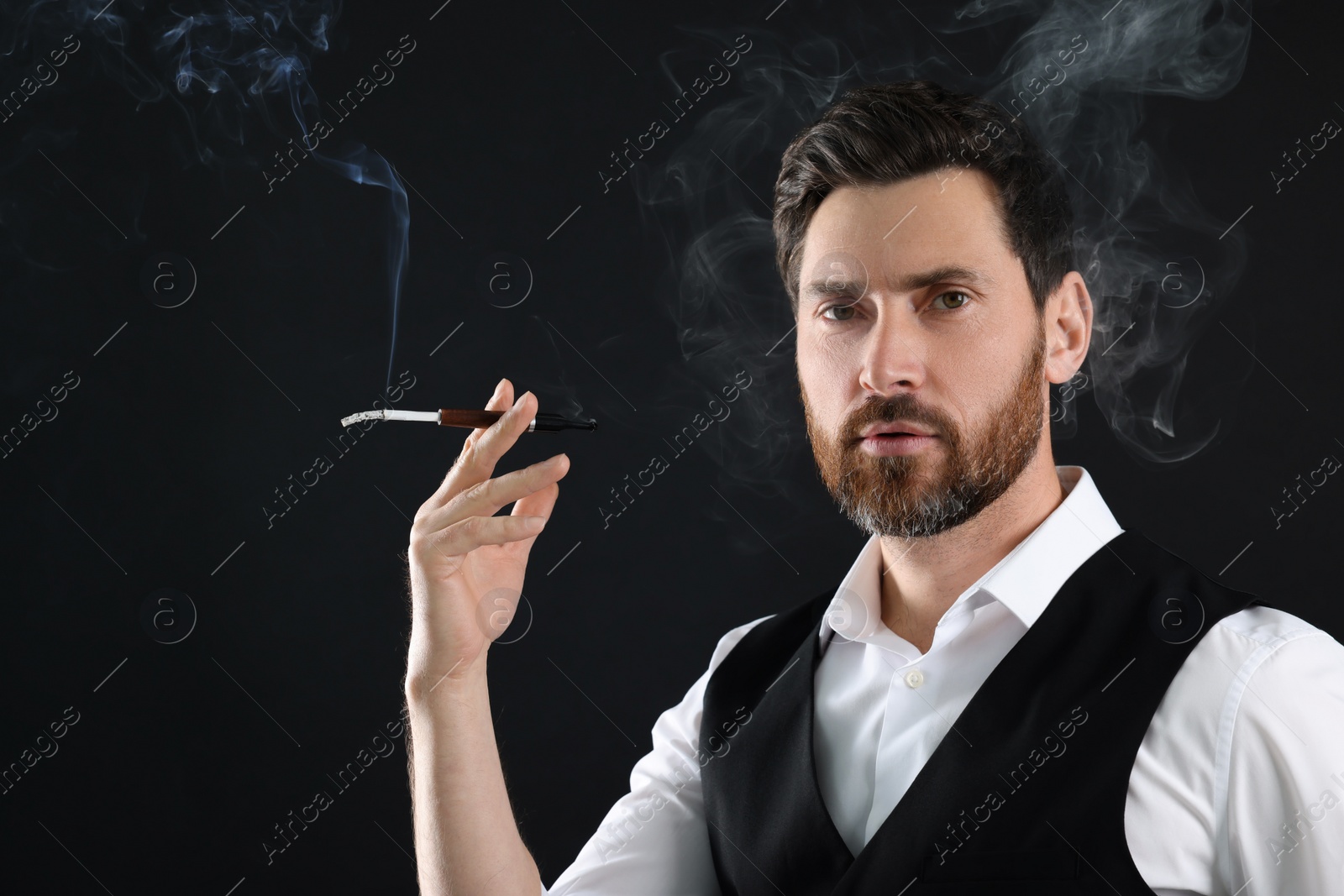 Photo of Man using cigarette holder for smoking on black background, space for text