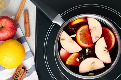 Photo of Delicious hot mulled wine on stove, flat lay