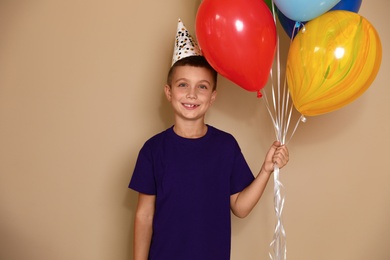 Happy boy with balloons on brown background. Birthday celebration