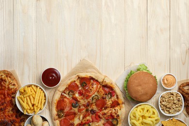 French fries, burger and other fast food on wooden table, flat lay with space for text