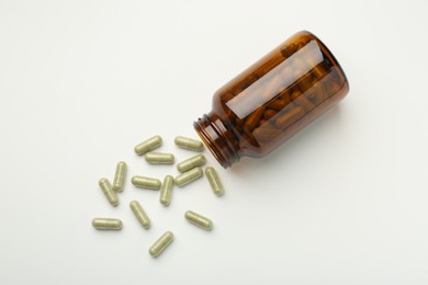 Bottle and vitamin capsules on white background, flat lay