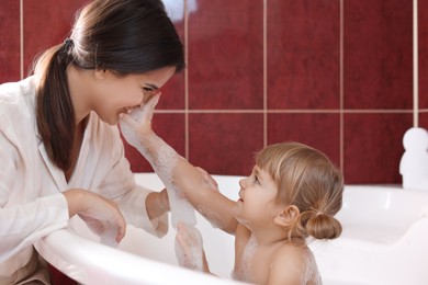 Photo of Happy mother with her little daughter spending time together in bathroom