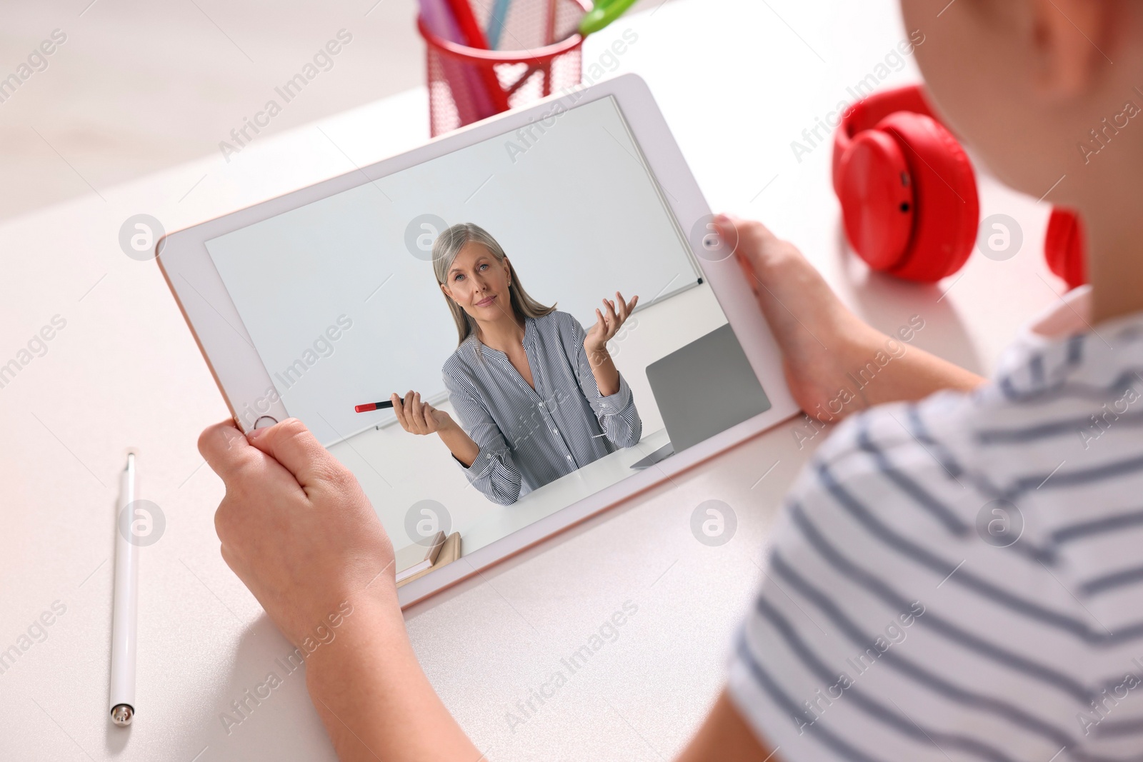 Image of E-learning. Little girl using tablet for studying online at table indoors, closeup