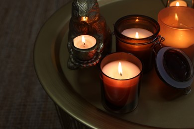 Burning candles in different holders on table indoors