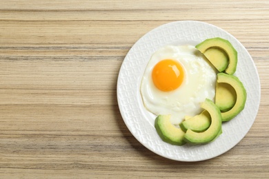 Photo of Delicious breakfast with fried egg served on wooden table, top view. Space for text