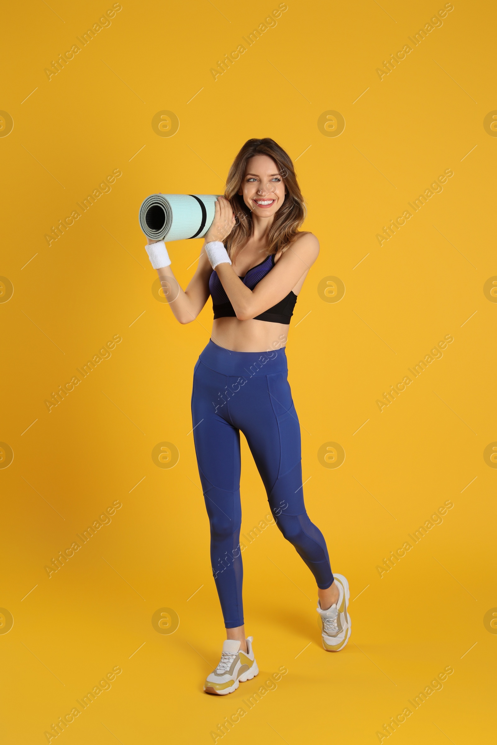 Photo of Beautiful woman with yoga mat on yellow background