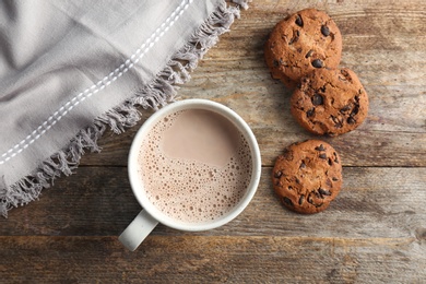 Mug with delicious hot cocoa drink and cookies on wooden table, top view