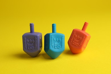 Photo of Colorful dreidels on yellow background. Traditional Hanukkah game