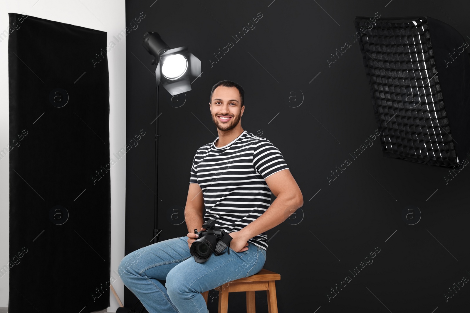 Photo of Young professional photographer with camera in modern photo studio