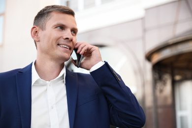 Photo of Businessman talking on phone near modern building