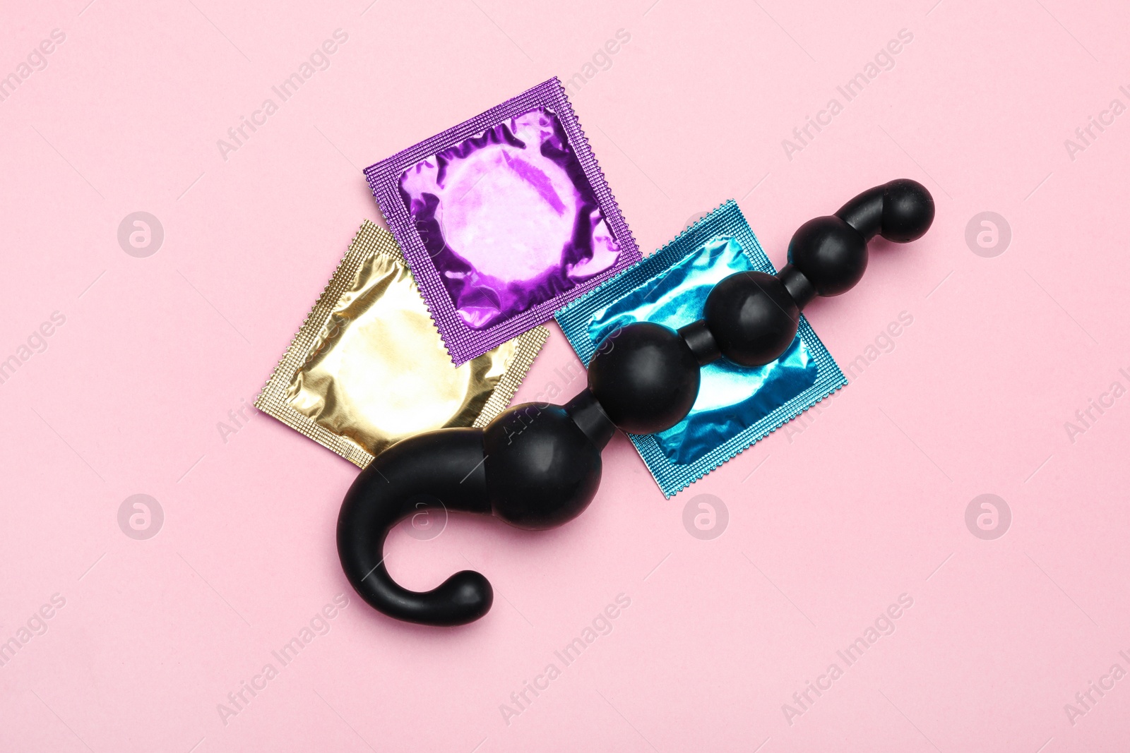 Photo of Anal ball beads and condoms on pink background, top view. Sex game