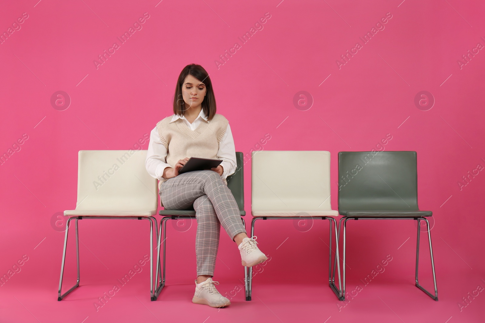 Photo of Young woman with tablet waiting for job interview on pink background