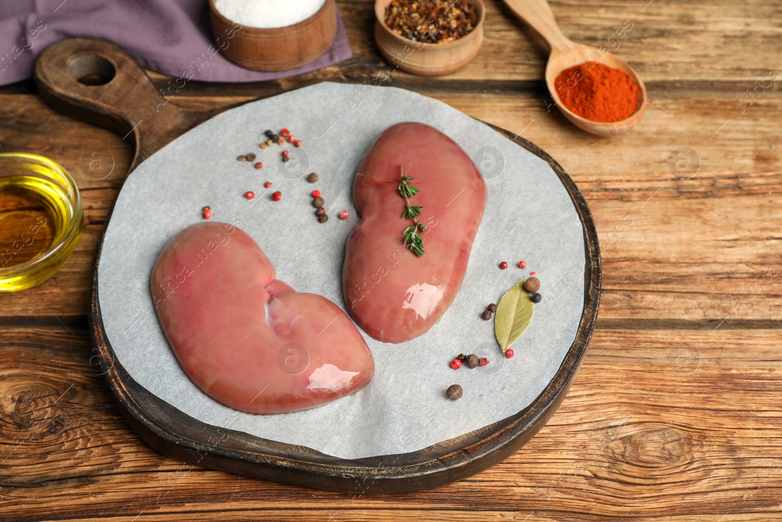 Photo of Fresh raw pork kidneys and ingredients on wooden table