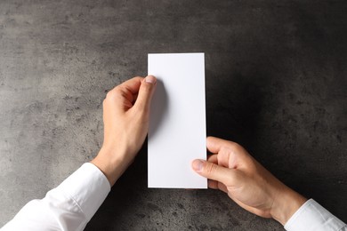 Photo of Man holding blank card at black textured table, top view. Mockup for design