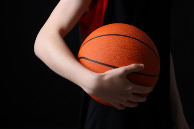 Photo of Boy with basketball ball on black background, closeup