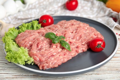 Photo of Raw chicken minced meat with basil and vegetables on white wooden table, closeup