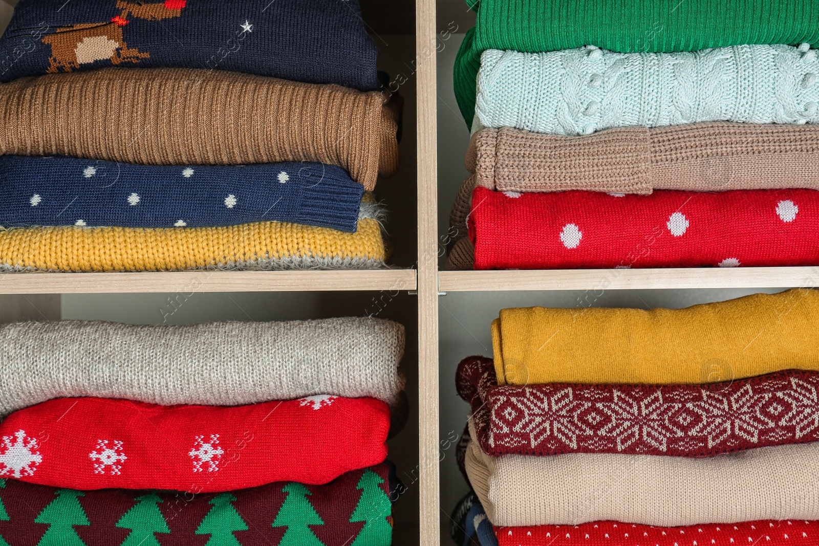 Photo of Folded winter clothes on shelves in wardrobe