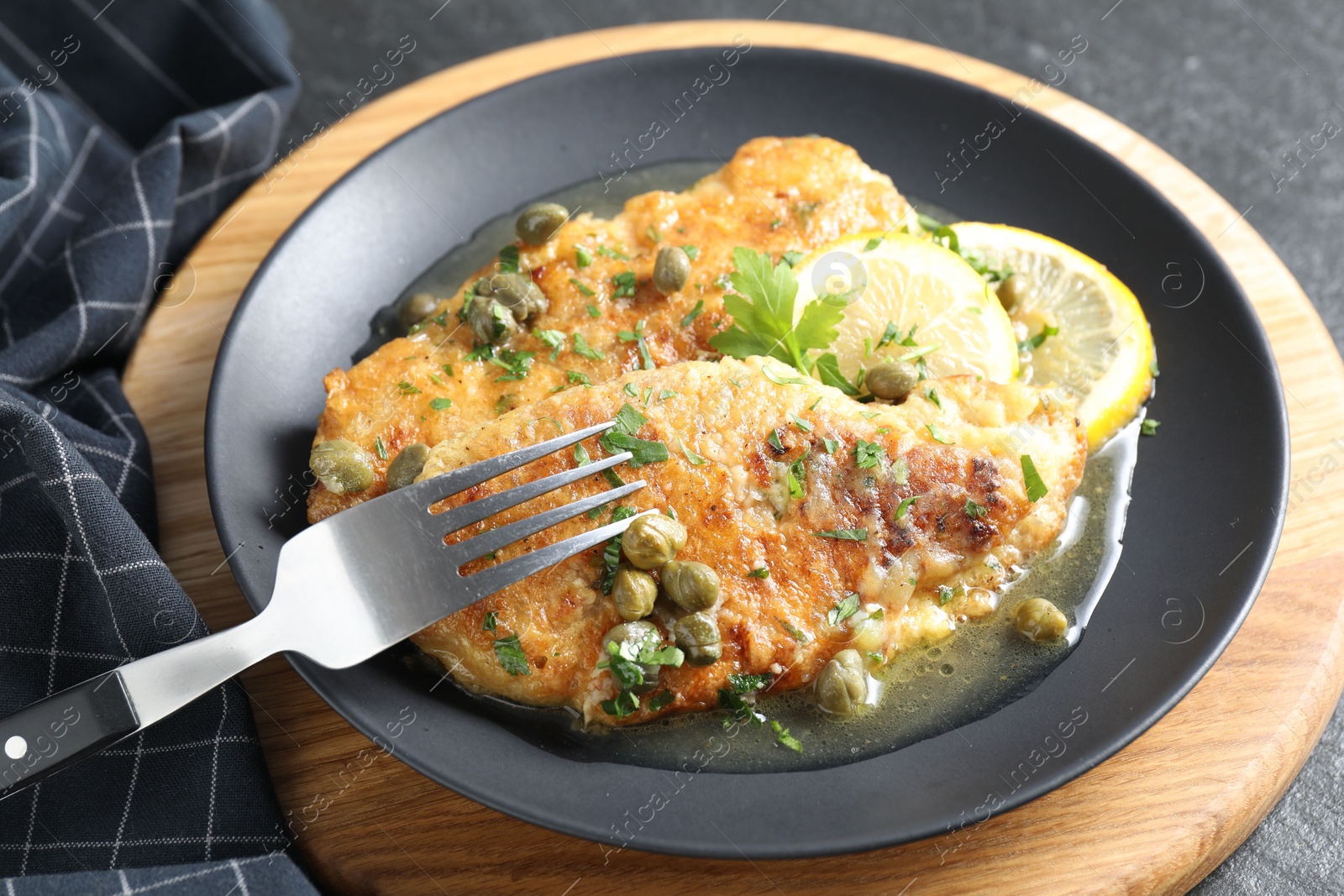 Photo of Delicious chicken piccata served on black table