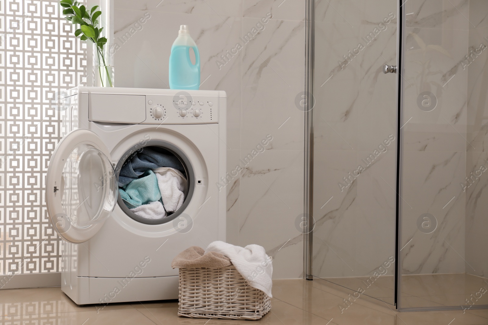 Photo of Modern washing machine with towels in bathroom