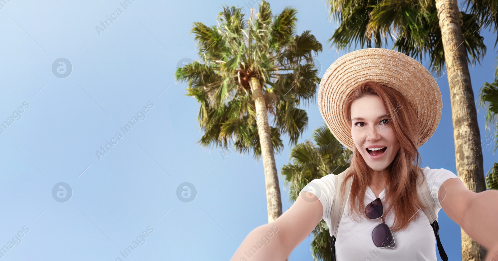 Image of Beautiful woman in straw hat taking selfie near tropical palms. Banner design with space for text