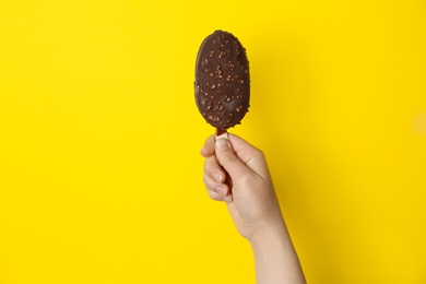 Photo of Woman holding delicious ice cream with chocolate against color background