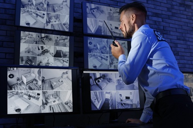 Photo of Male security guard with portable transmitter monitoring modern CCTV cameras indoors