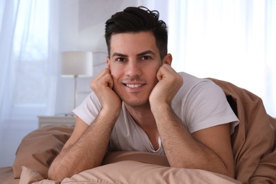 Photo of Man lying in comfortable bed with beige linens