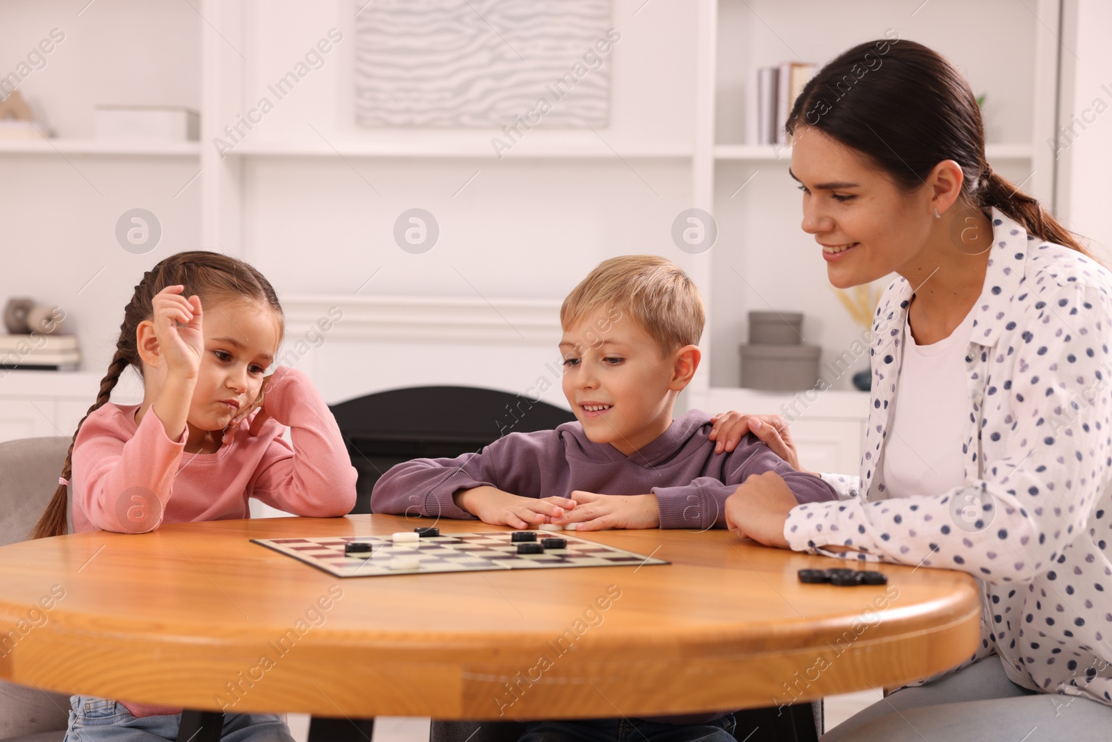 Photo of Family playing checkers at wooden table in room