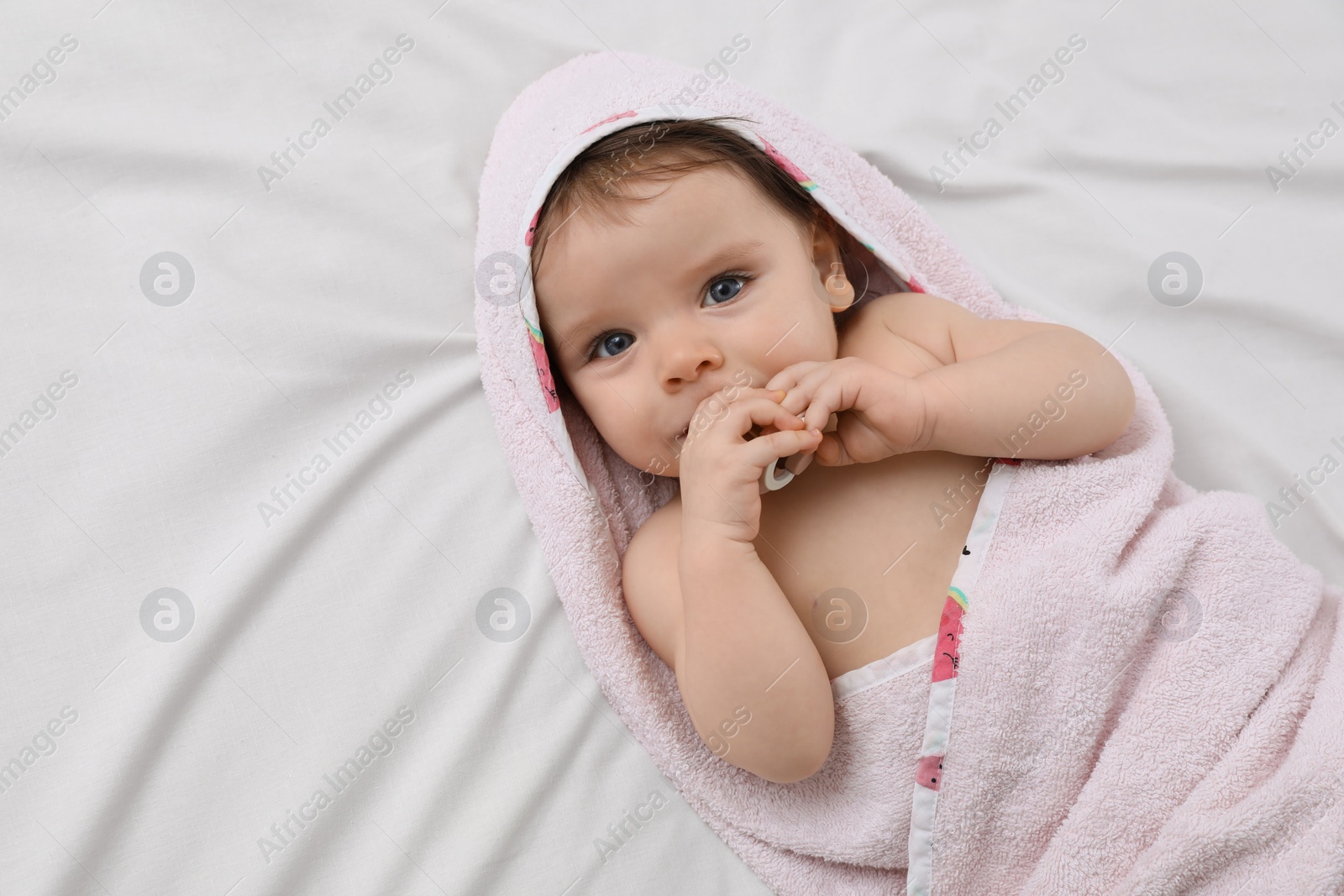 Photo of Cute little baby with pacifier in hooded towel after bathing on bed, top view