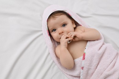 Cute little baby with pacifier in hooded towel after bathing on bed, top view